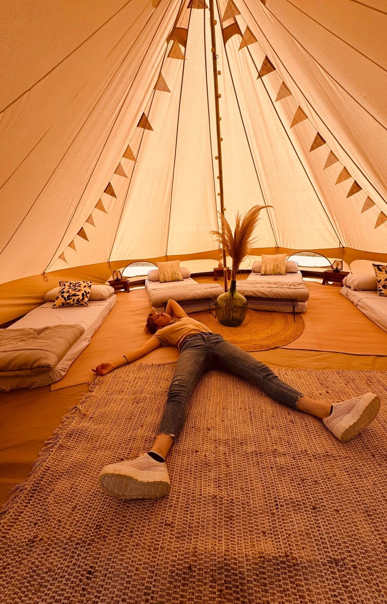 a woman laying on a rug in a glamping tent, la sensacion
