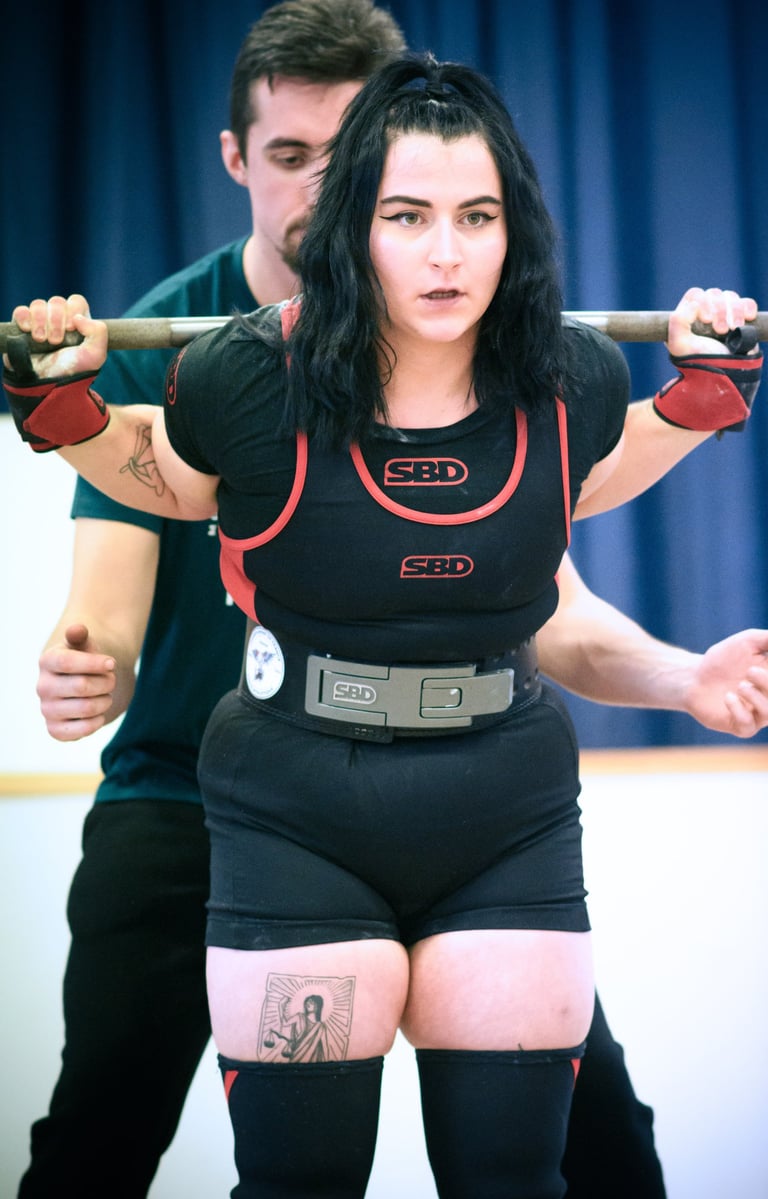 Une jeune femme en singlet pratiquant le squat pour une compétition de powerlifting