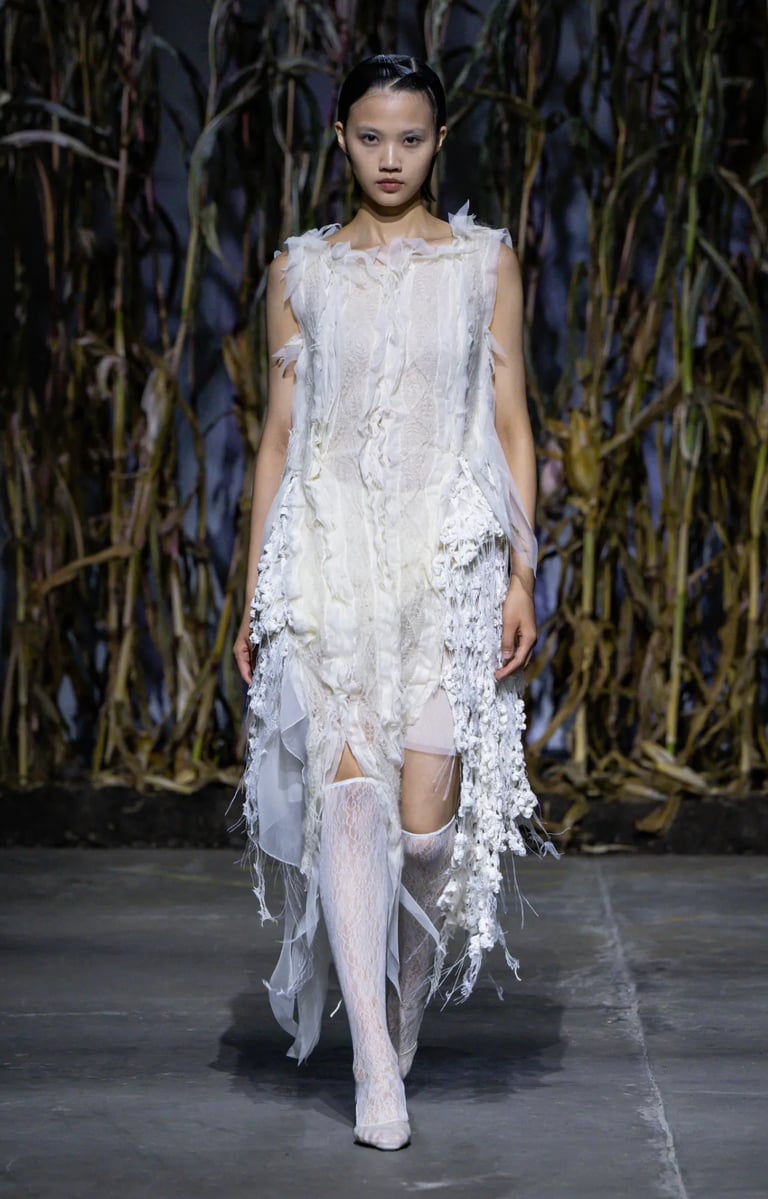 a woman in a white dress and stockings on a runway