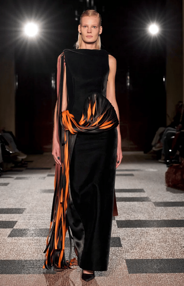 Roksanda model in black gown with orange ribbon detailing on the runway at London Fashion Week 2026.