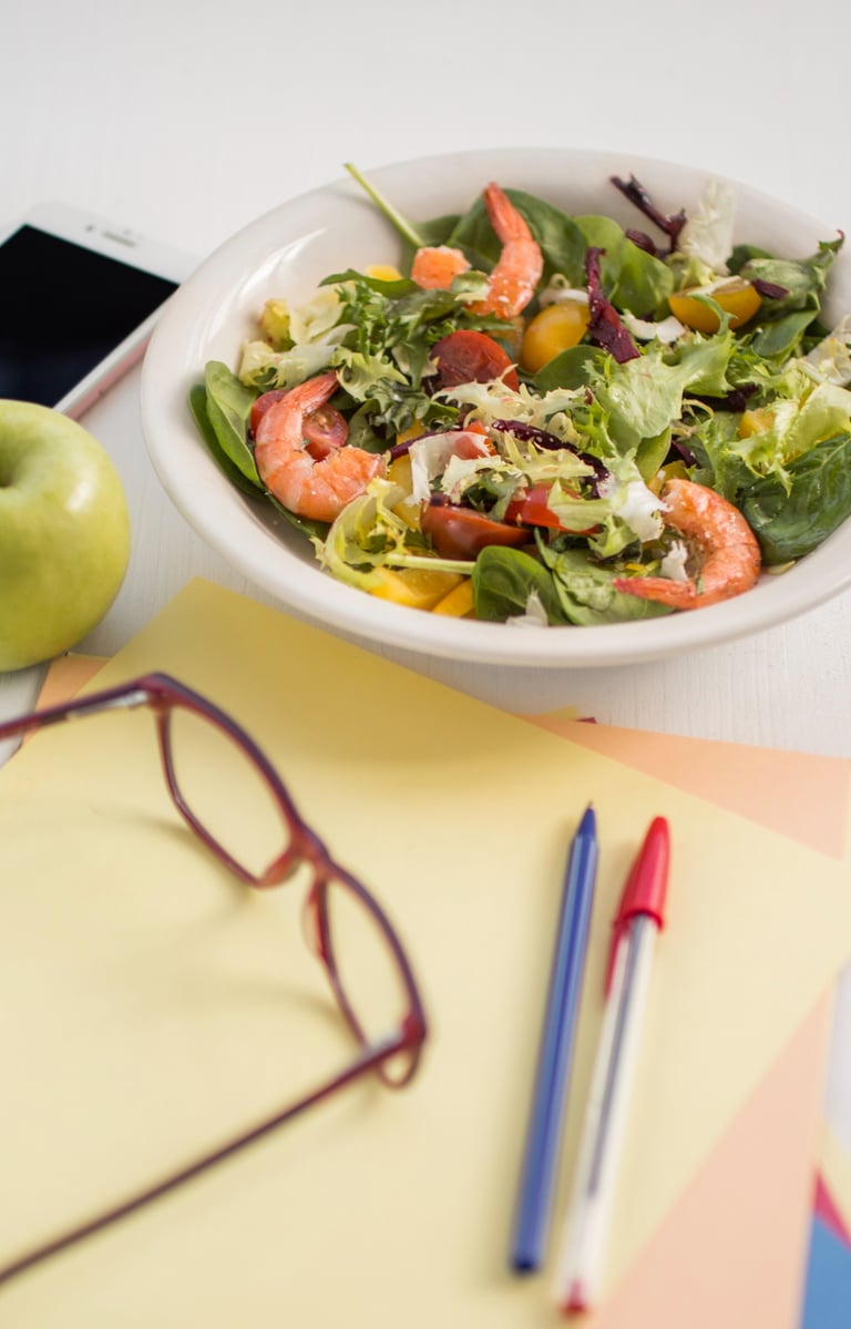 ensalada, hojas de papel y bolígrafos en una maesa