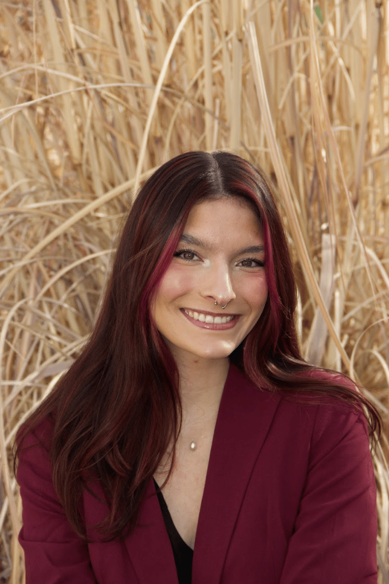 Headshot of Quesada Stoner in a maroon suit.