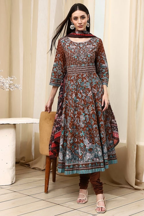 Woman wearing a brown floral print Anarkali kurta set with matching dupatta and churidar leggings.