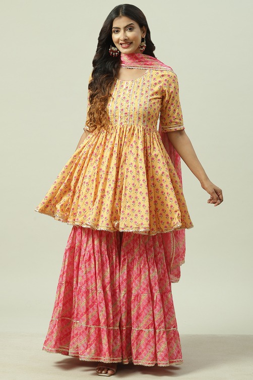 Woman wearing a yellow and pink floral print Anarkali kurta with matching sharara pants and dupatta.