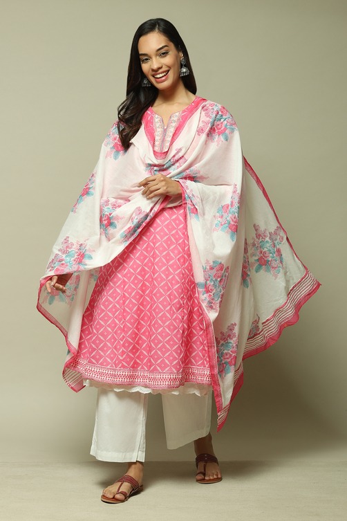 Woman wearing a pink printed cotton kurti with floral dupatta and white palazzo pants for ethnic style.
