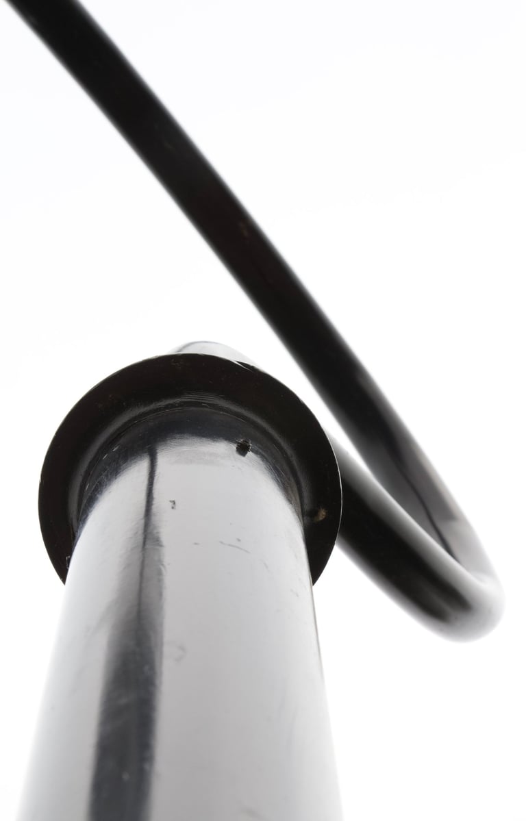 Black & white metal pole with curved part resembling a hook on a white sky..