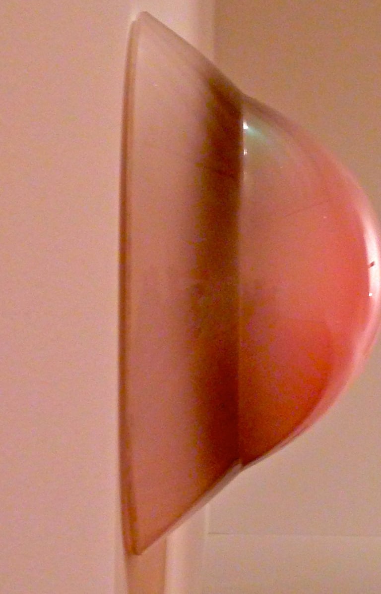 Pinkish-reddish plastic round pyramid-like wall protector reflecting light.