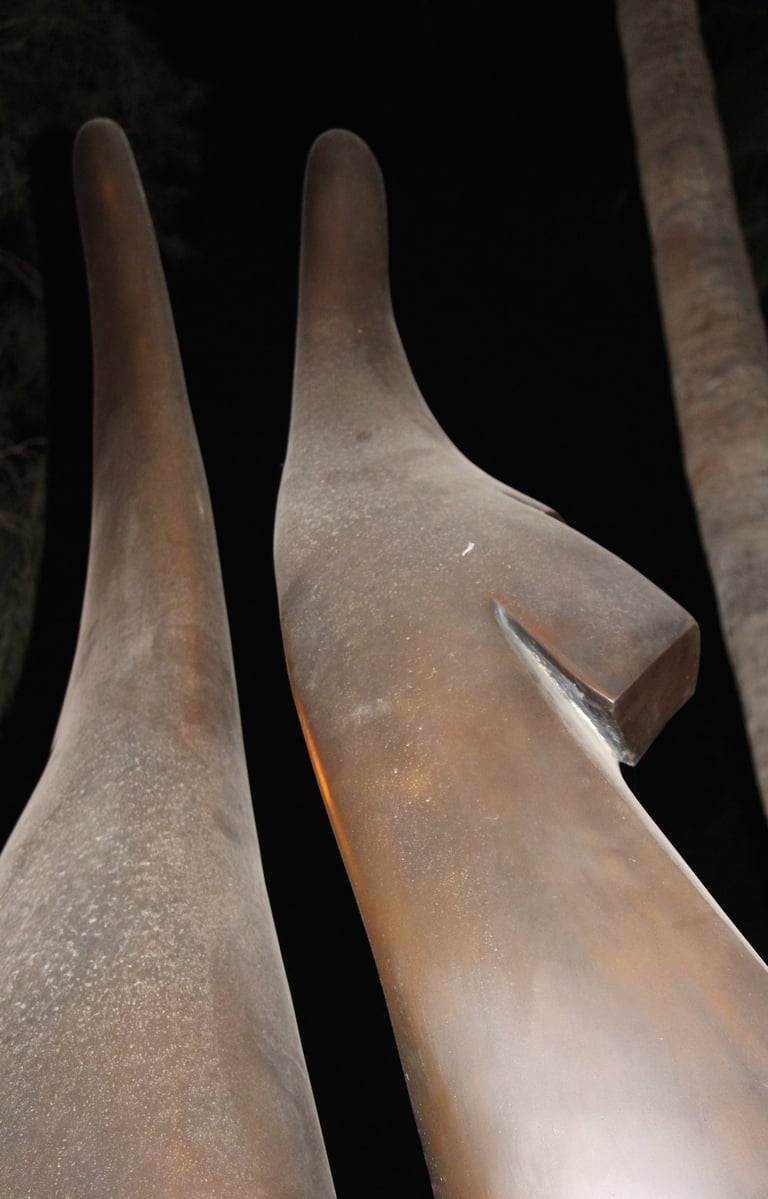 Two sculpture-like brownish long protrusions pointing upwards into a dark space.. 