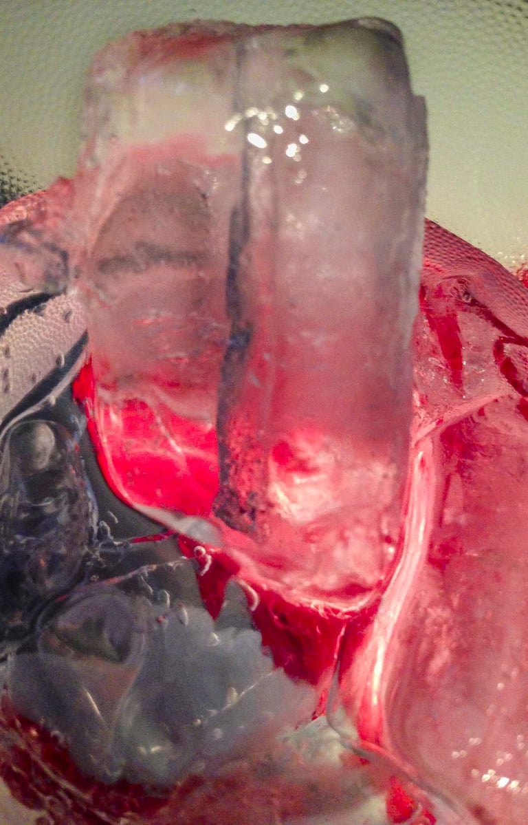 Several melting ice cubes of different sizes and shapes, in a plastic clear cup.