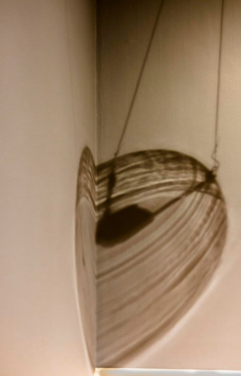 Out of view light fixture casting linear brownish shadows in the corner of the wall.