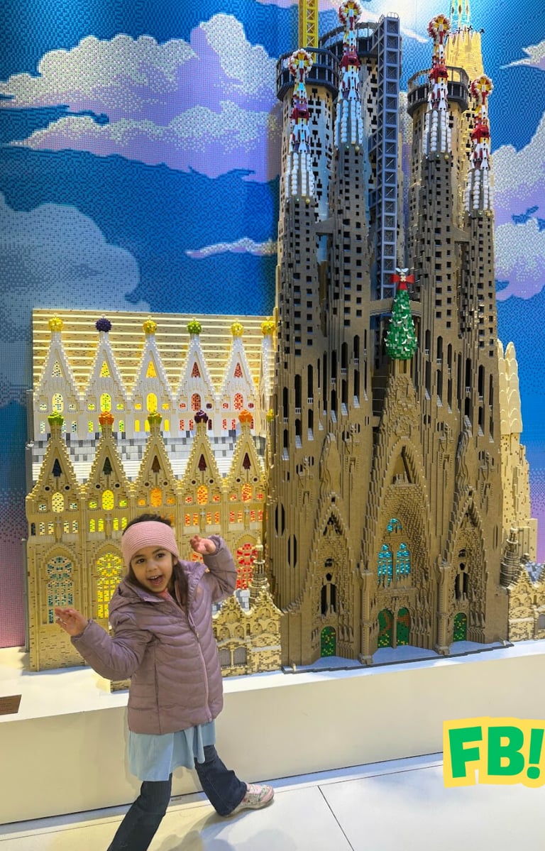 a little girl standing in front of a lego - like building