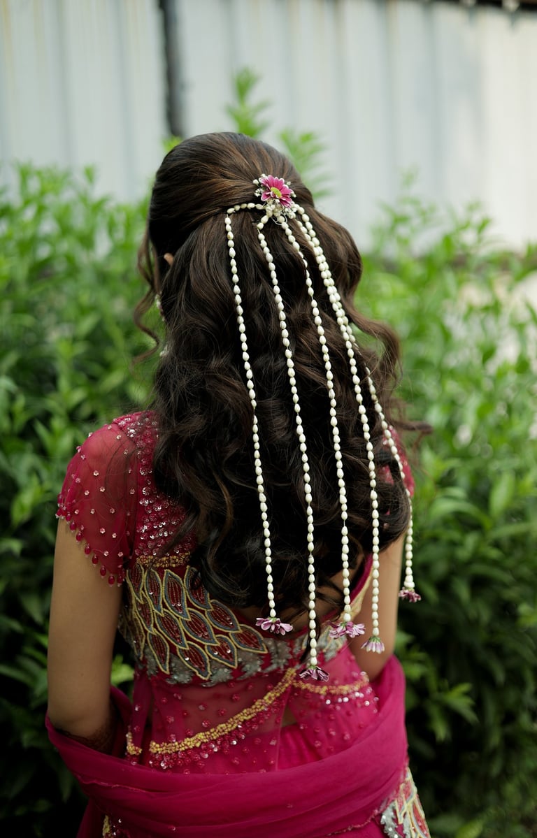 Open variation bridal hairstyle with white floral strings and pink flower clip by professional brida