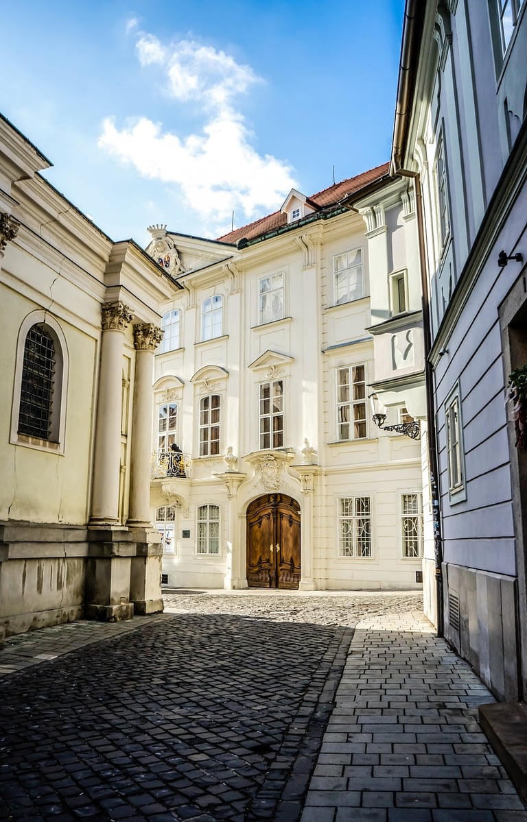 Fachada de un edificio barroco blanco en el centro histórico de Bratislava, al final de una calle ad