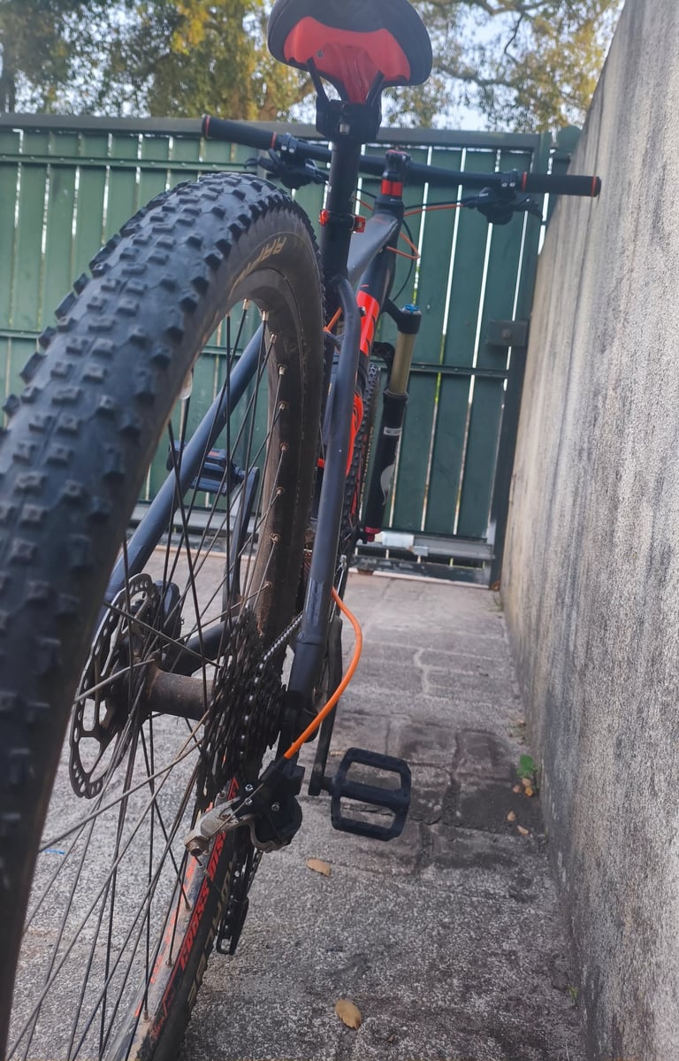 Roda traseira e transmissão de bicicleta MTB KTM com pneu de piso agressivo e pedal preto, vista lat