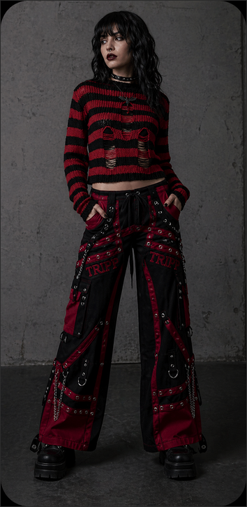 Woman wearing gothic Tripp NYC bondage pants and a red striped distressed sweater.