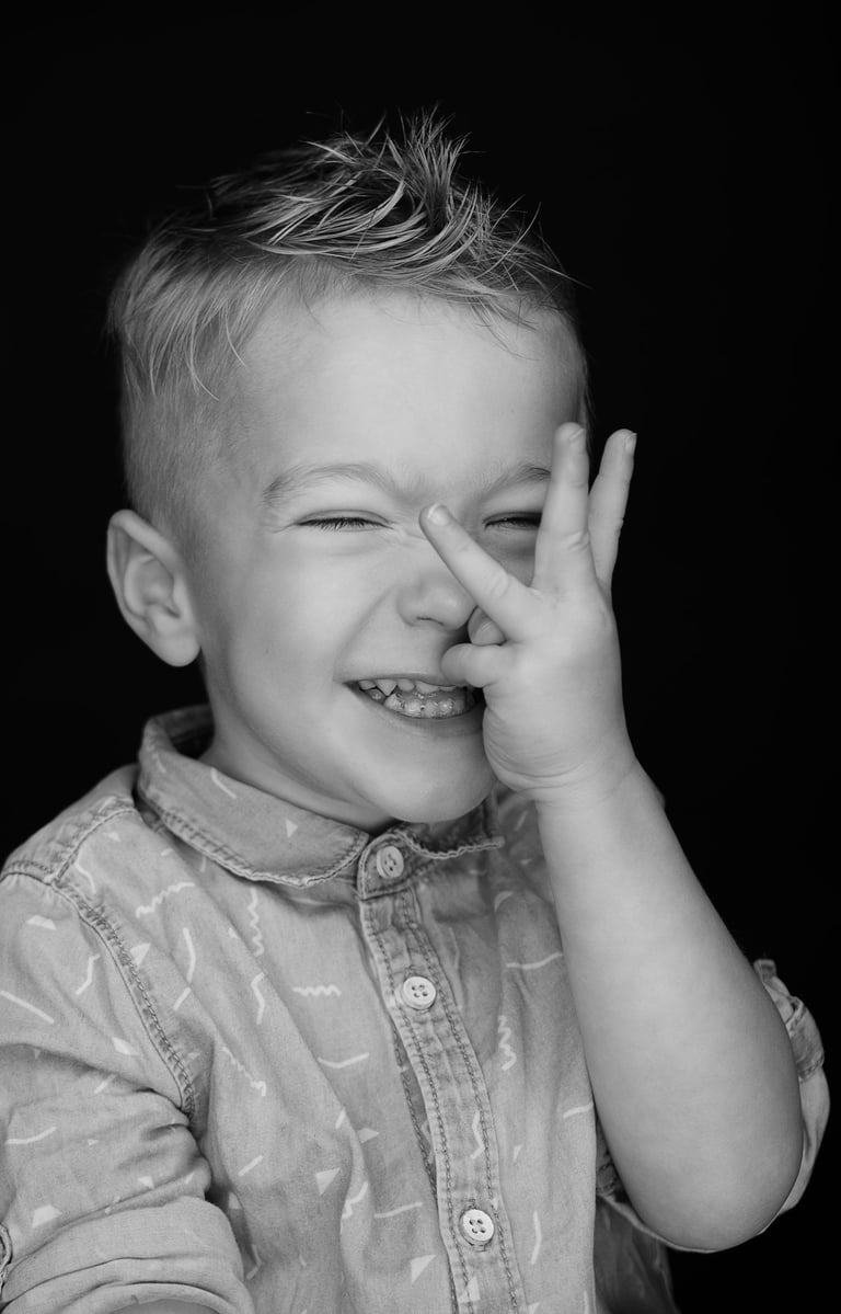 portret a young boy with a his fingers in to look between the eyes