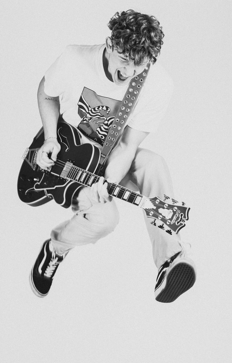 a man in a white shirt and tie dye on a guitar