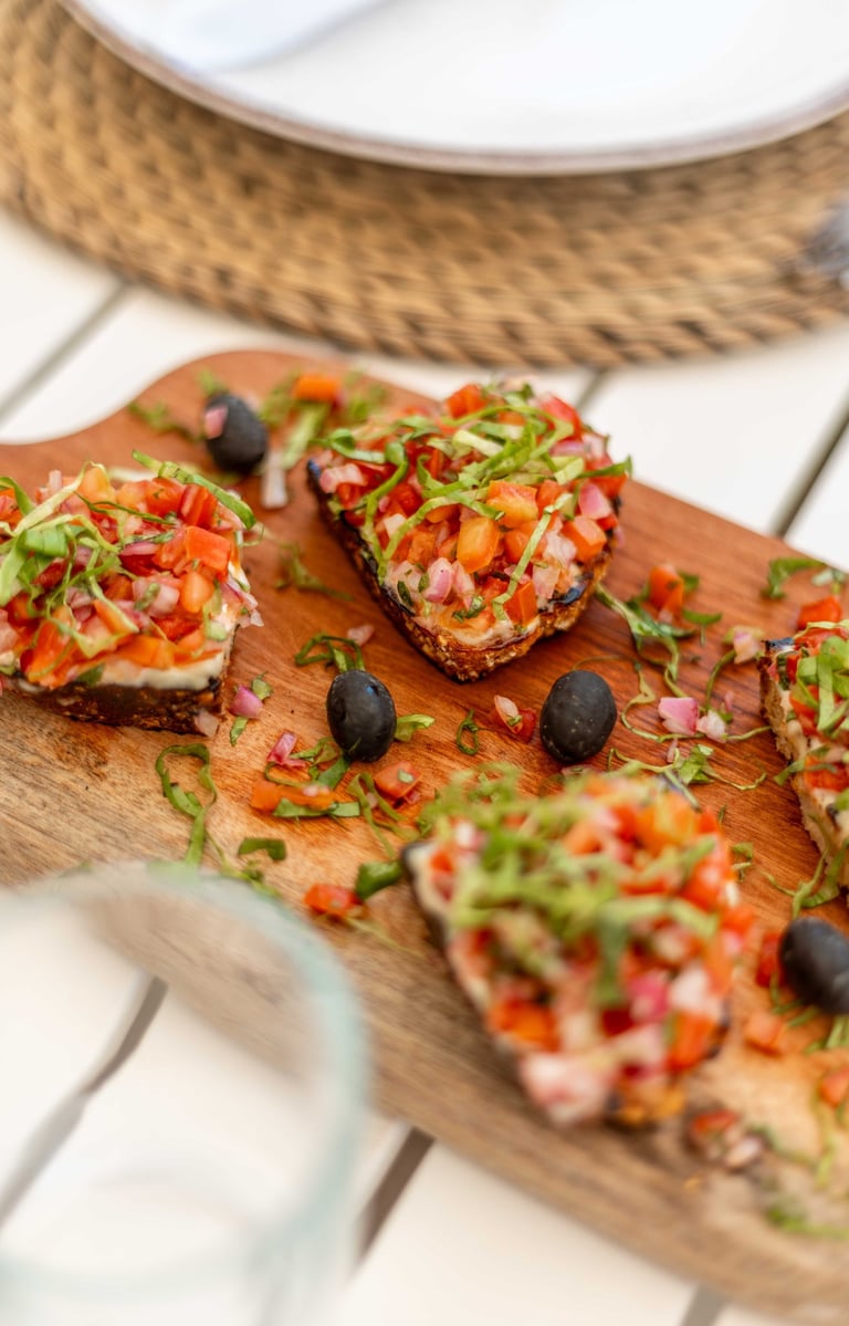 a wooden board with bruschetta appetizer and a glass of wine