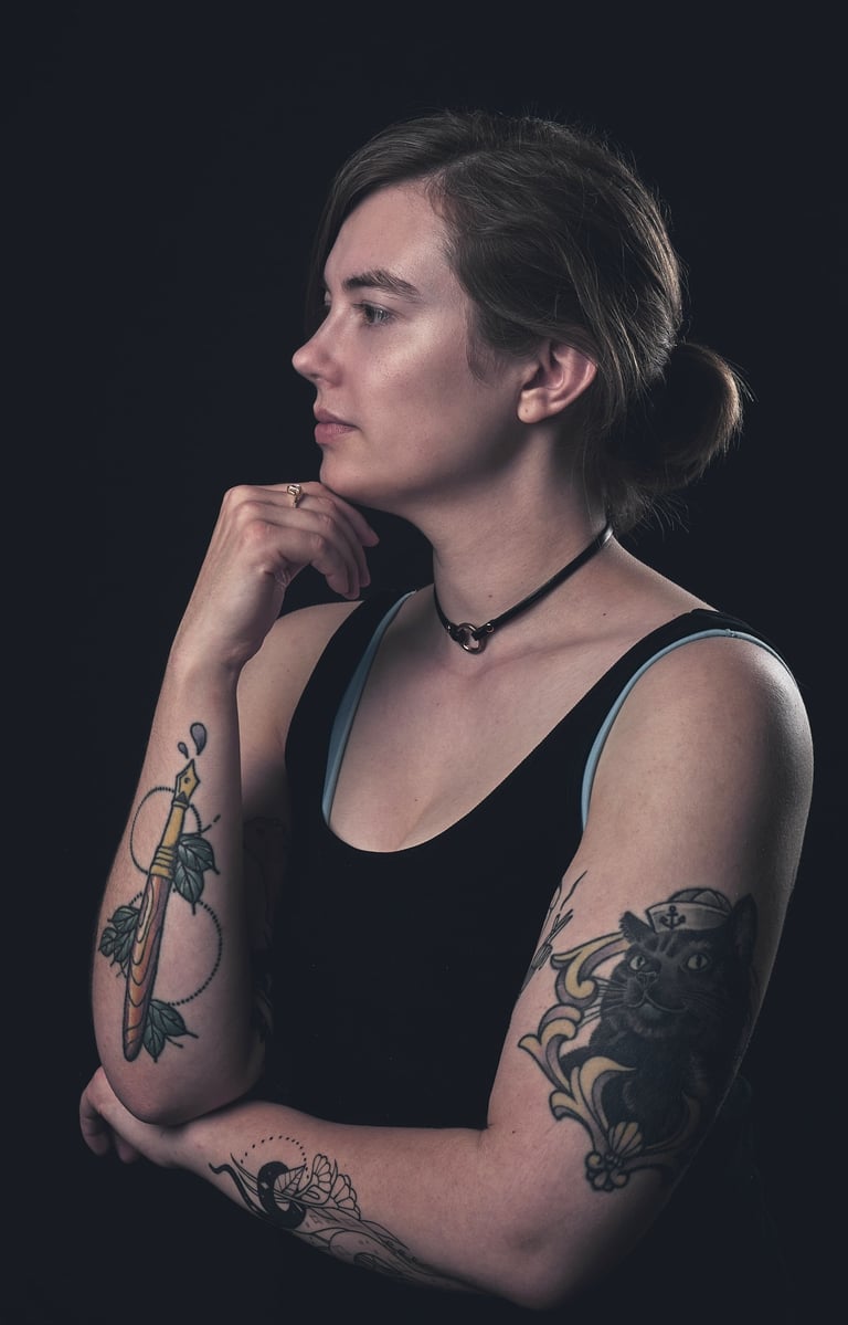 a woman with tattoo of a pen on her right arm and a cat tattoo on her left arm