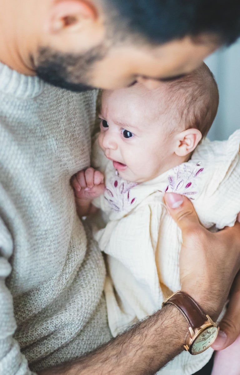 Photographe bébé Levallois : bébé dans les bras de son papa