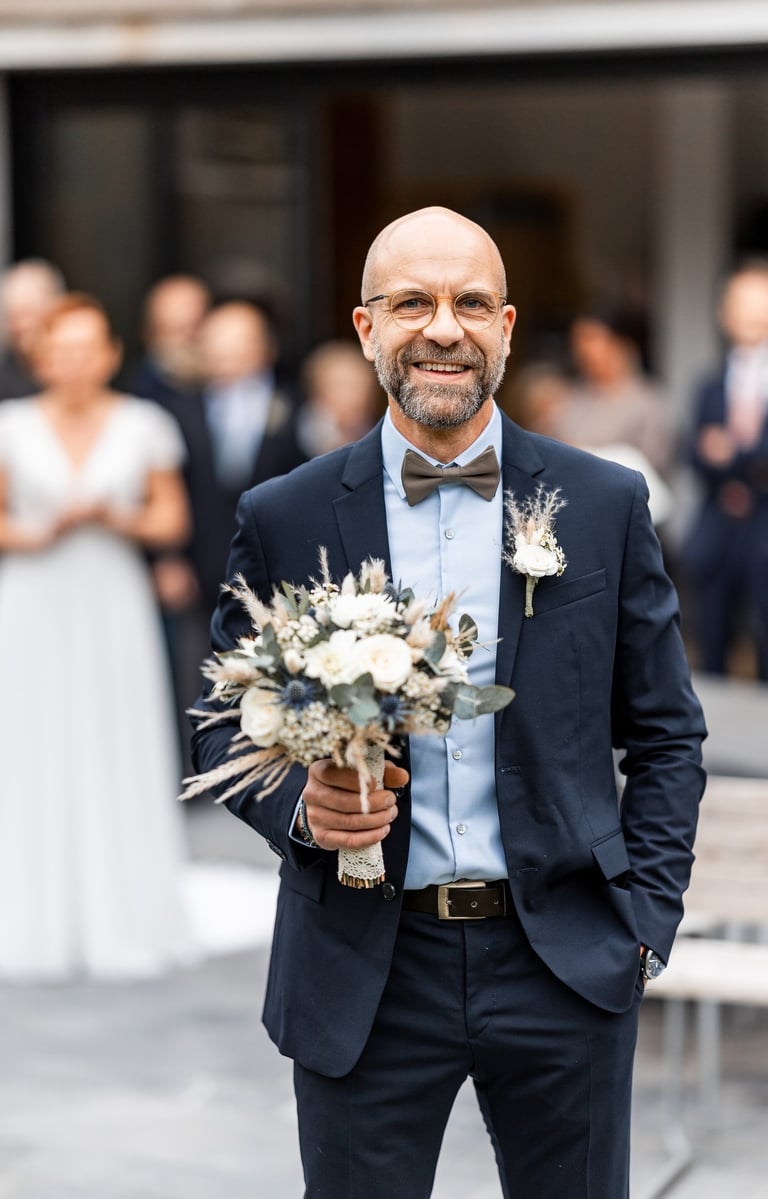 Un homme en costume avec un bouquet de fleurs à la main
