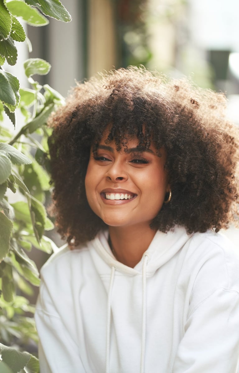 A Black girl with long curly hair and a communicative smile posing during a photo session