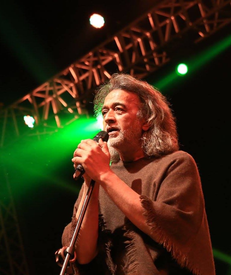 a man in a brown shirt is holding a microphone