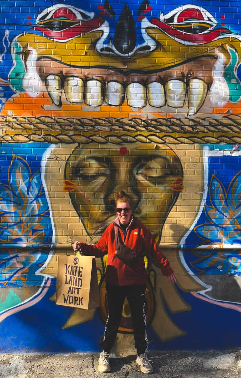 Artist Kate Land in front of vibrant street art