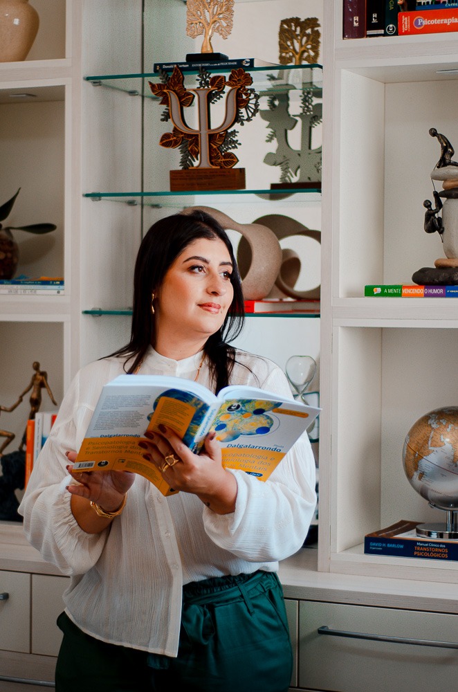 Psicóloga Luciana Boechat Bohn lendo livro na frente da estante