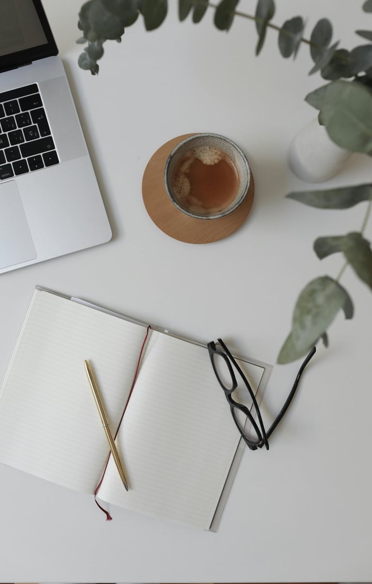 Workspace of a business operations support specialist with a laptop, coffee, and notebook