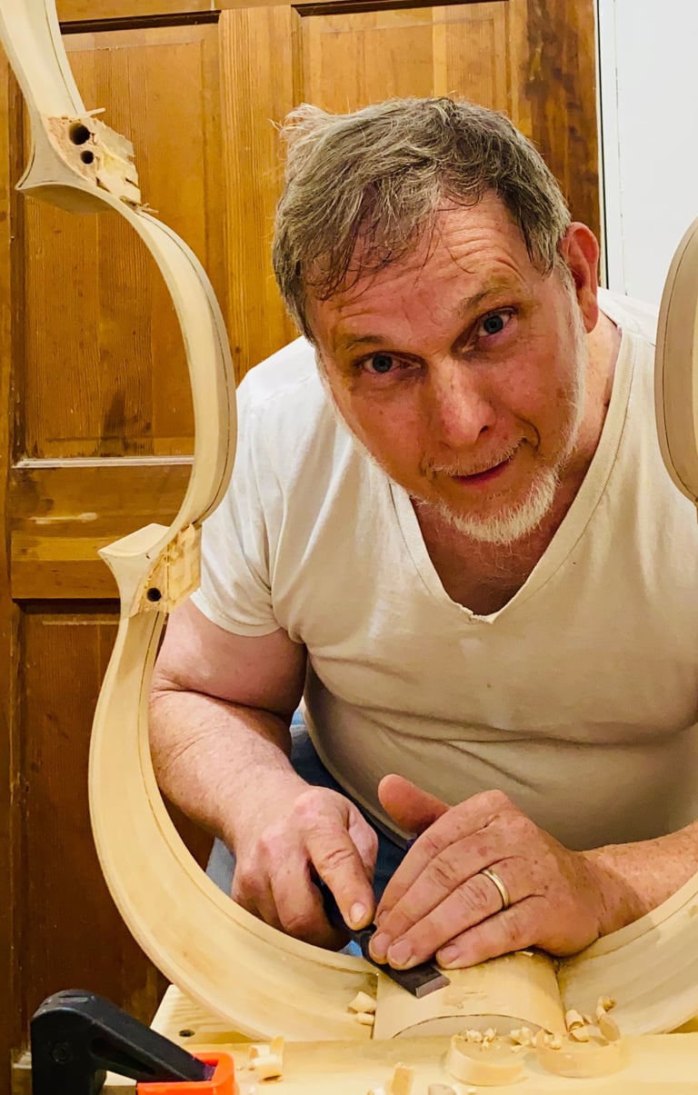 Jim Clinton peering with a smile, through a cello rib skeleton