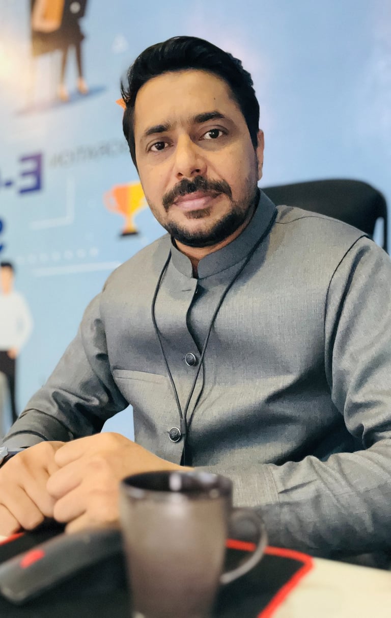 Professional male entrepreneur in a gray waistcoat sitting at an office desk with a coffee mug.