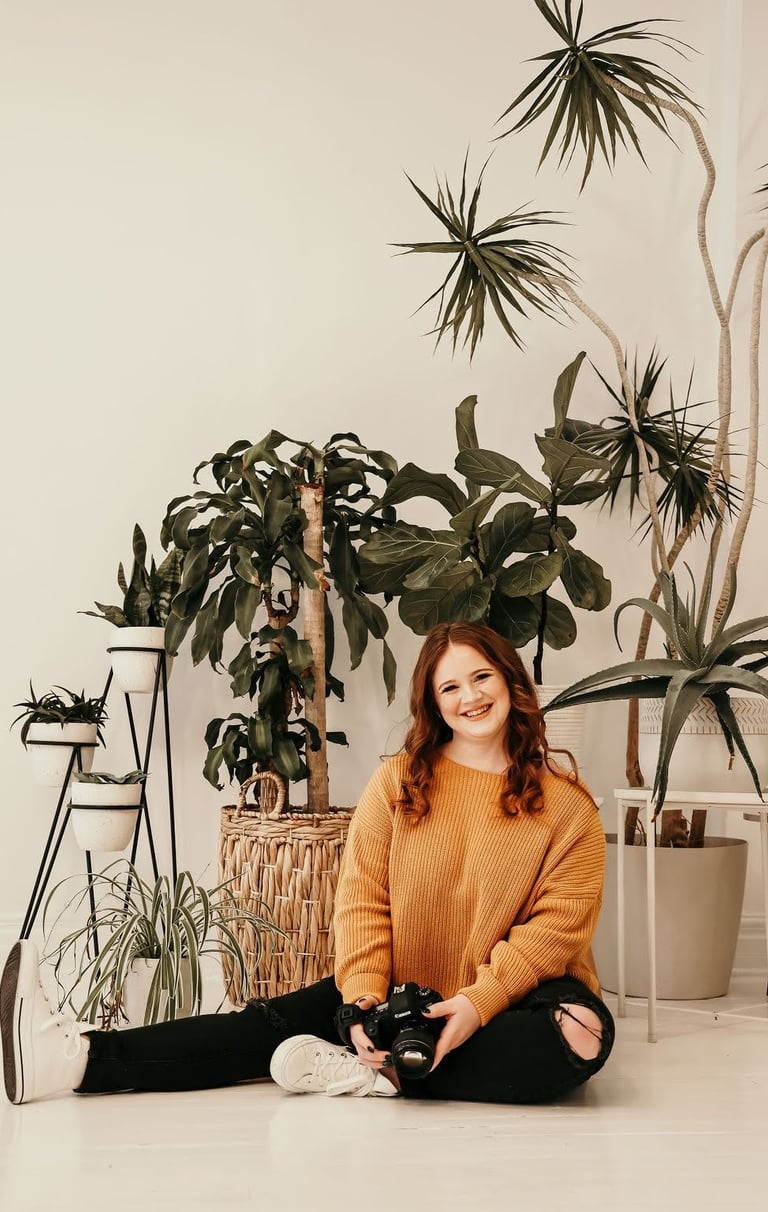 Rachel smiling and sitting in front of indoor plants
