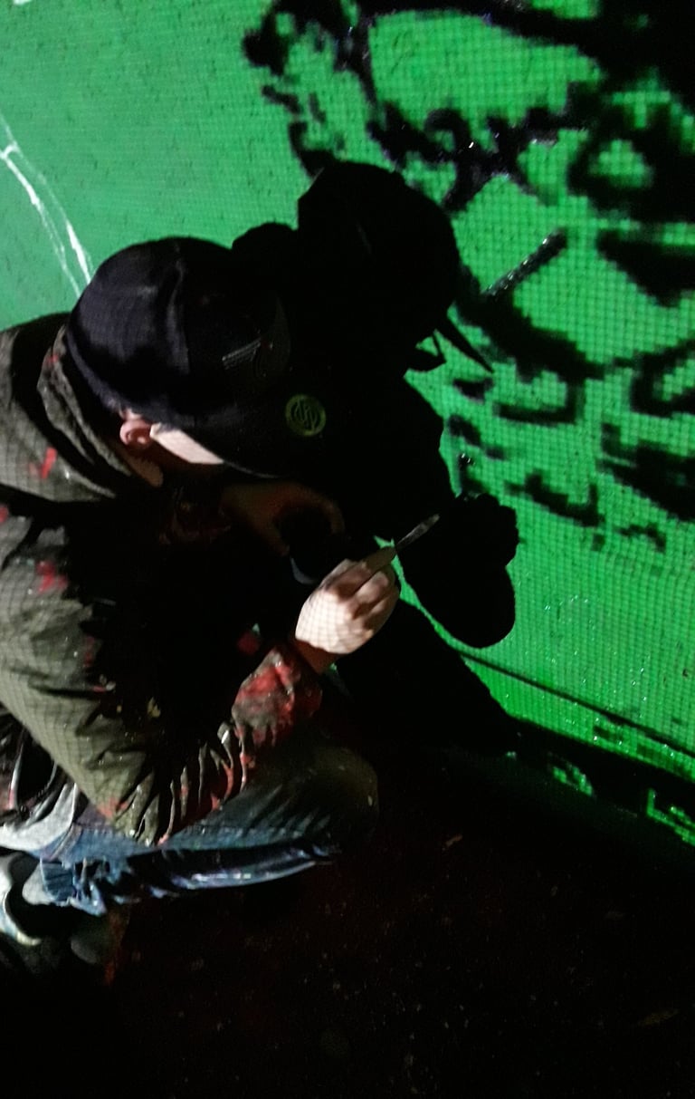 Artist working on a green-wall mural at night, an urban painting created by Poliops.