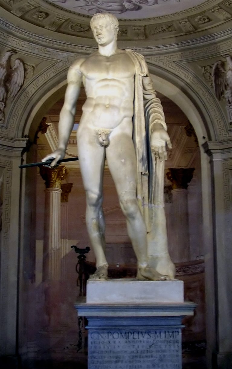 Full-length ancient Roman marble statue of a heroic nude male figure standing in a classic pose inside a vaulted alcove.