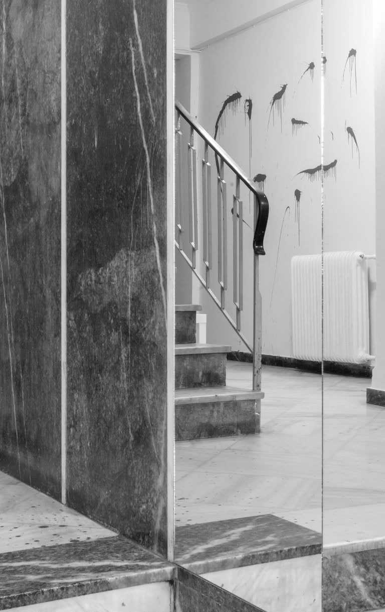 A staircase leading to a staircase in a building with paint smudges on the walls and floor