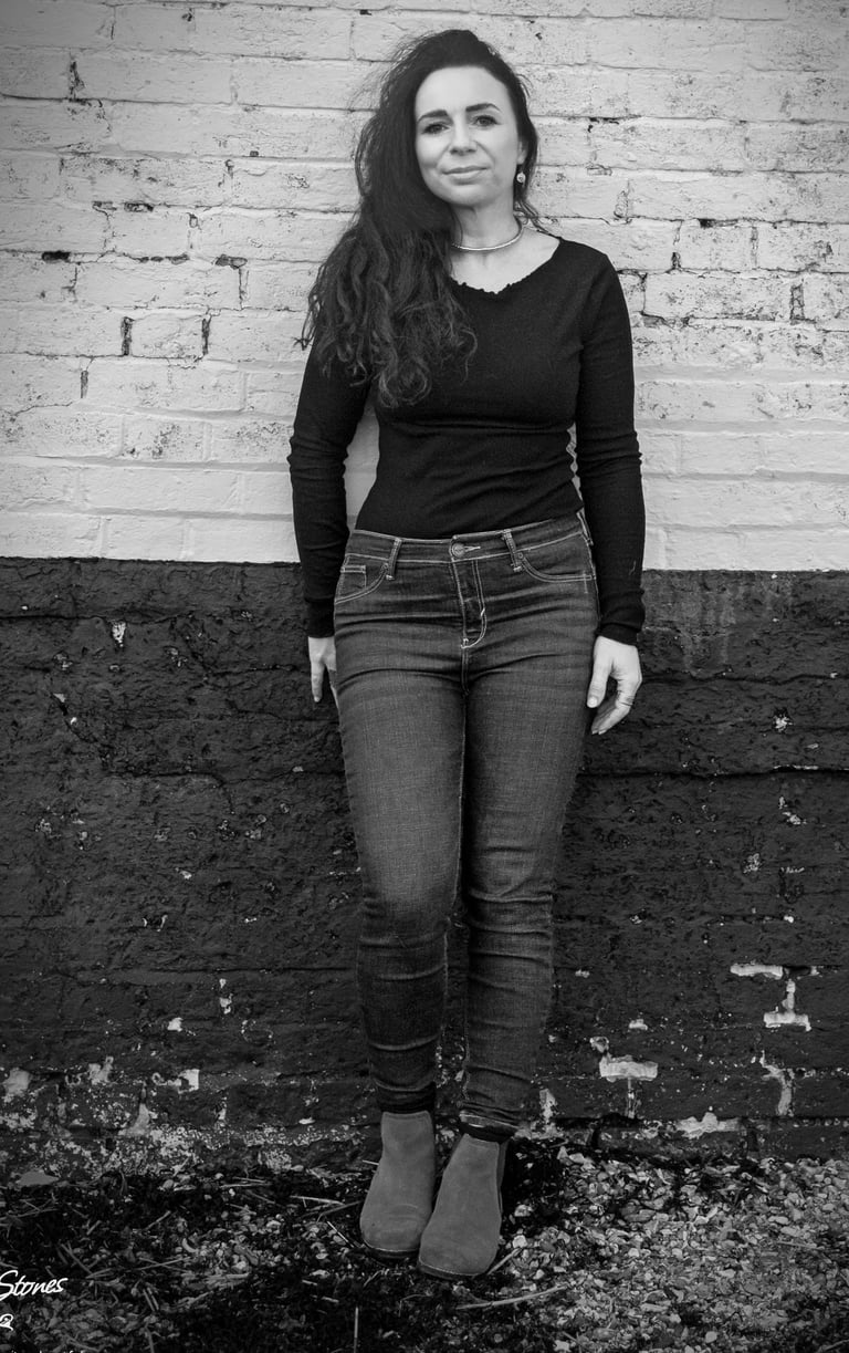 Black and white portrait of Helen Spooner, pianist and vocalist, standing against a brick wall.