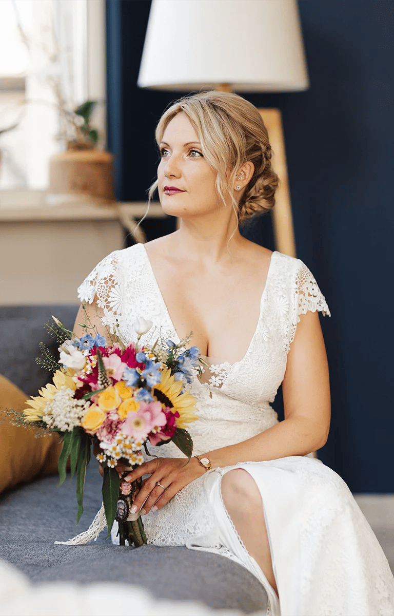 Mariée pensive tenant son bouquet coloré avant la cérémonie.