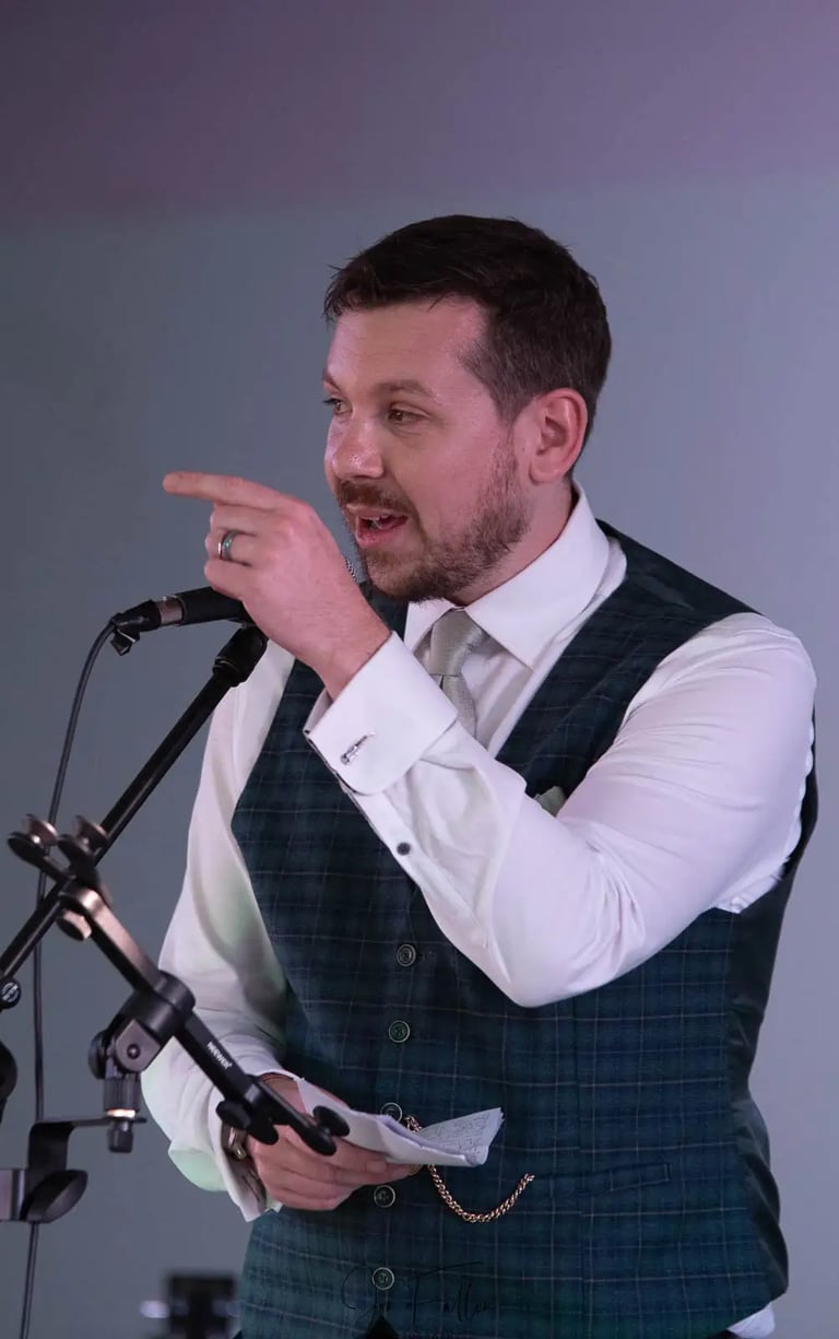 Groom in a green plaid vest delivering a speech.