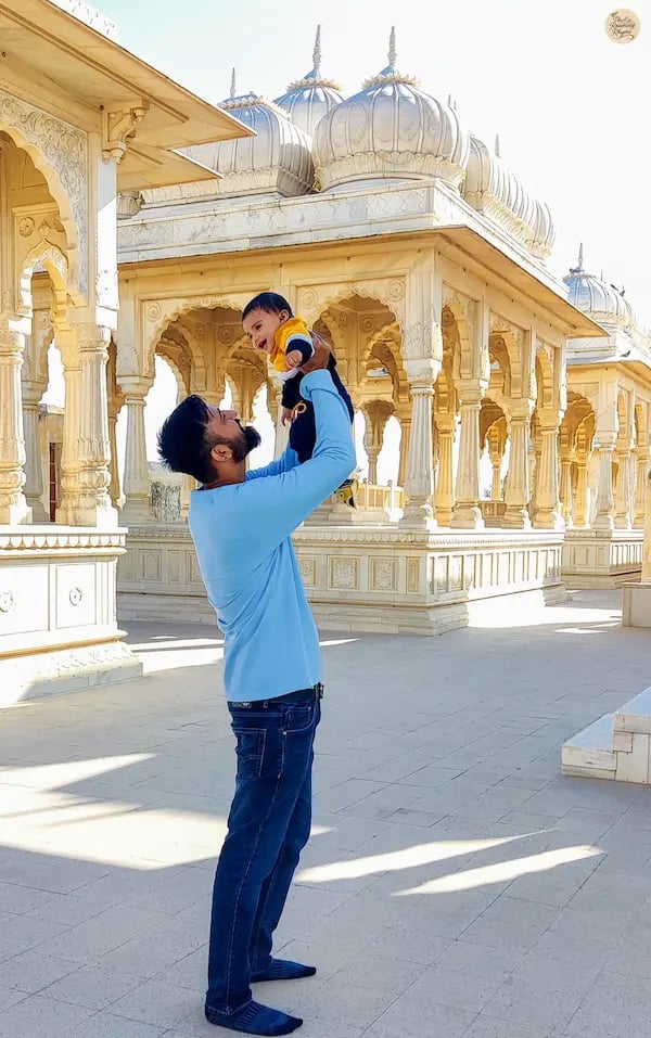 Parent with toddler at Devi Kund Sagar, surrounded by marble chhatris of royal heritage