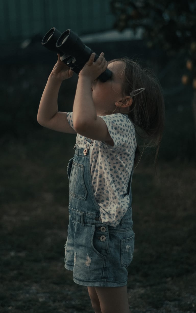 Fotografía de una niña mirando al cielo con prismáticos