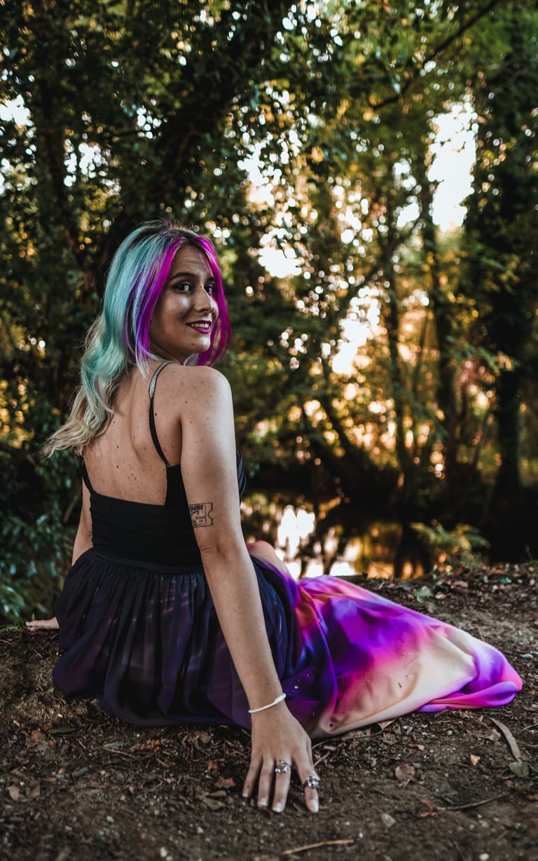 Fotografía de una mujer con vestido en el bosque, al lado del río
