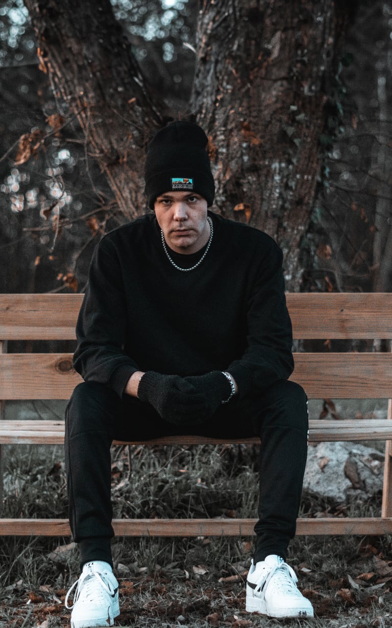 Fotografía de un hombre sentado en un banco, vestido de negro