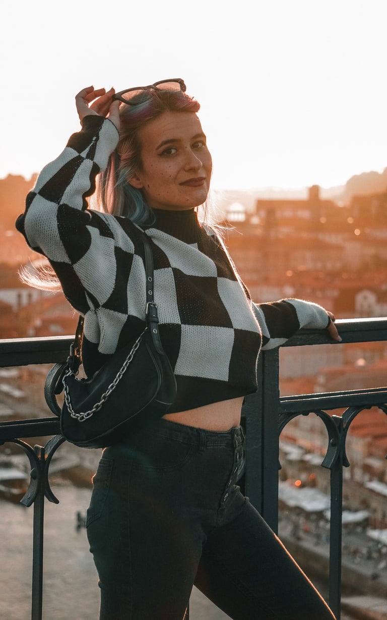 Fotografía de una mujer posando en el puente de Oporto, con la puesta de sol al fondo