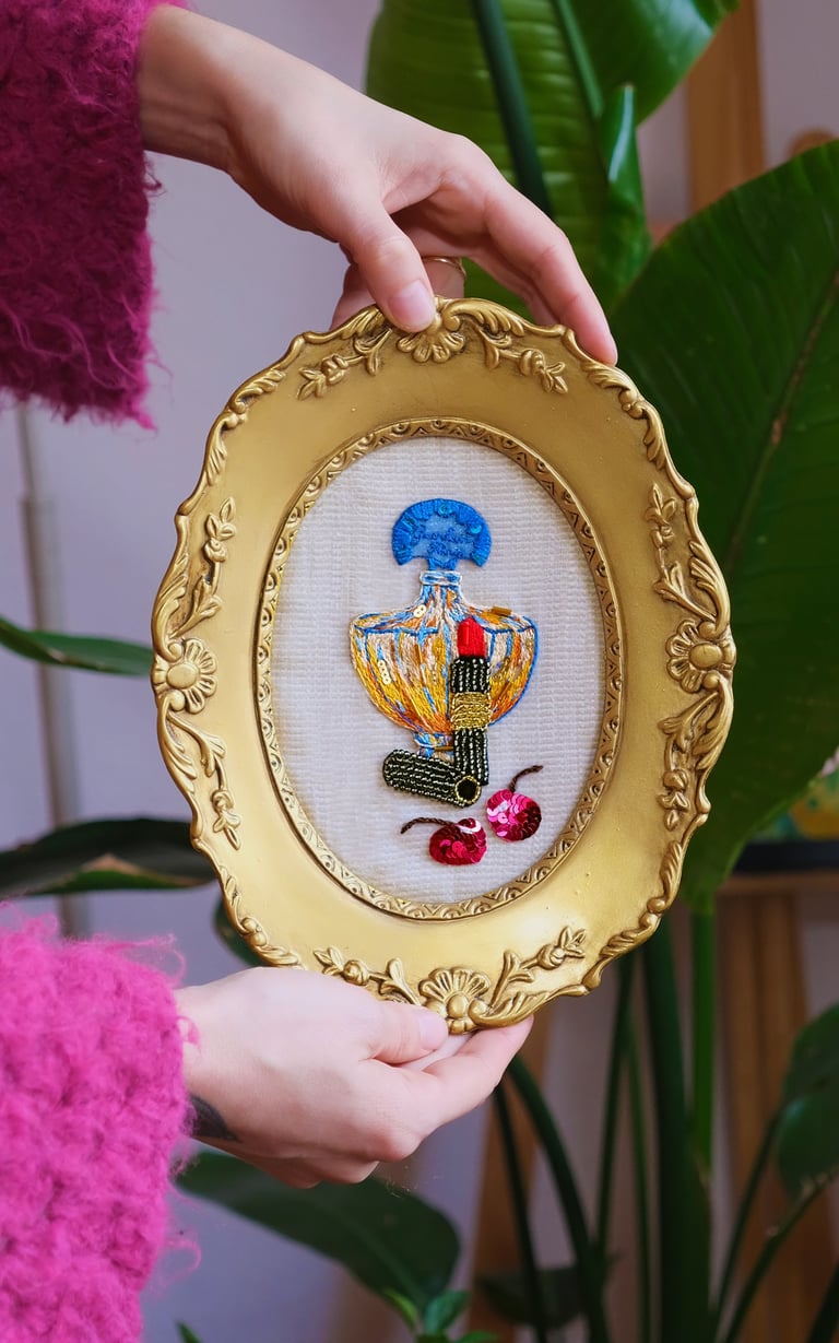 feminine embroidery of a perfume (Shalimar) and red lipstick, very chic in vintage frame