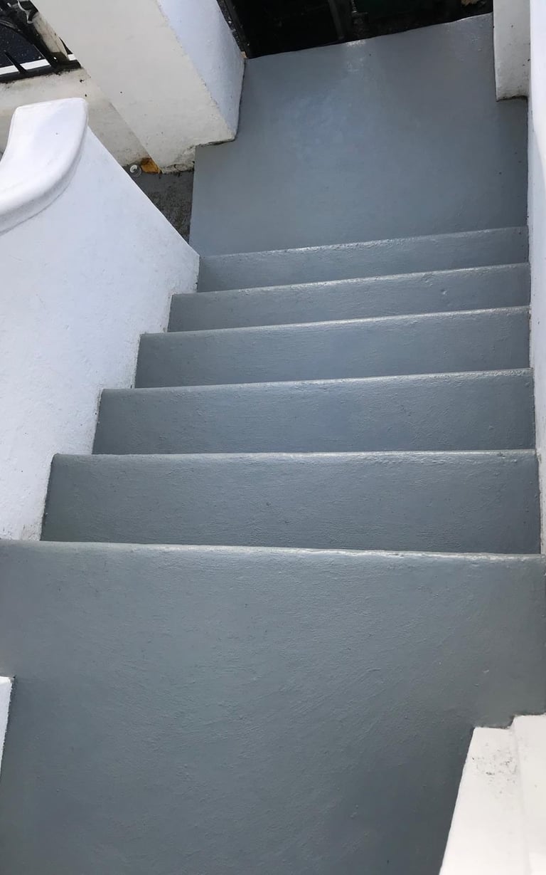 Freshly painted grey concrete stairs with white masonry walls for modern outdoor entryway in Sussex.