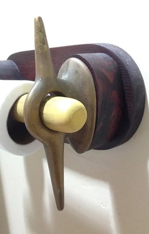 Side view of a toilet paper holder made of two brass cleats.