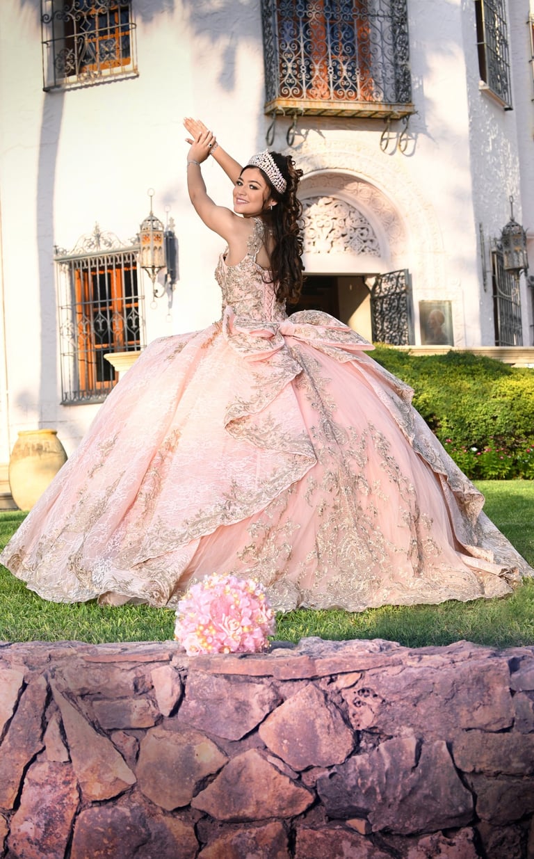a woman in a pink dress sitting on a stone wall