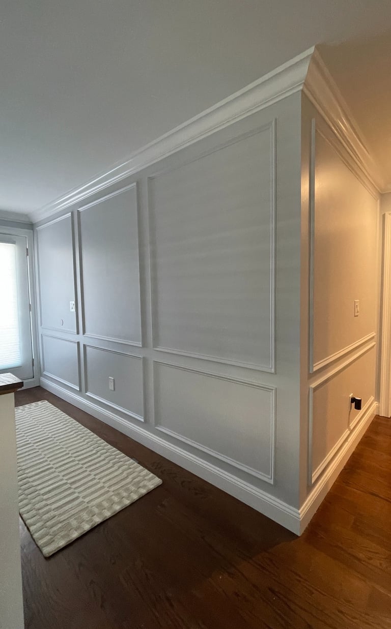 Custom white wall paneling with picture-frame molding and crown molding in a Monmouth County NJ
