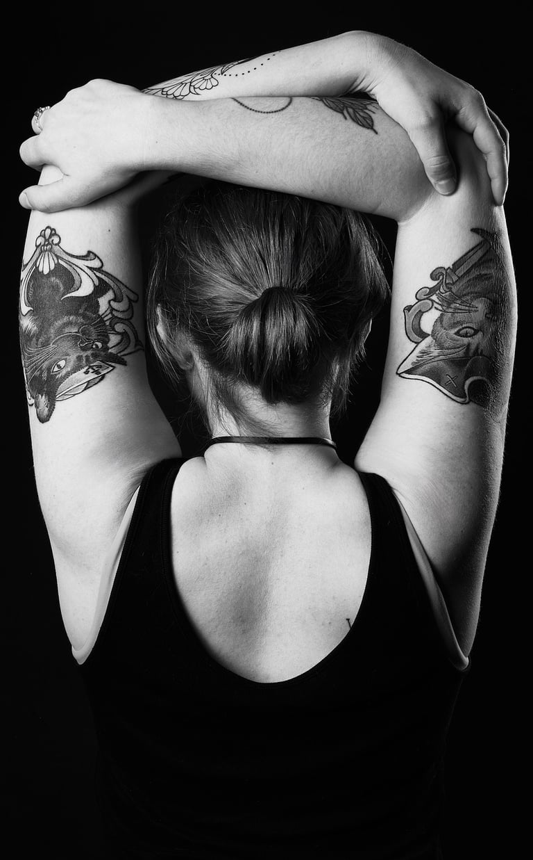 a woman showing her back with cat tattoos on her arms which are stretching around her head